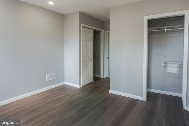 unfurnished bedroom with dark hardwood / wood-style flooring and a closet