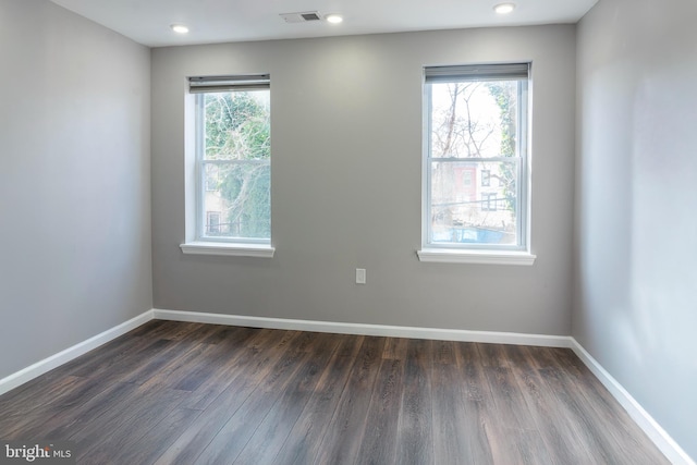 spare room with dark hardwood / wood-style flooring and plenty of natural light