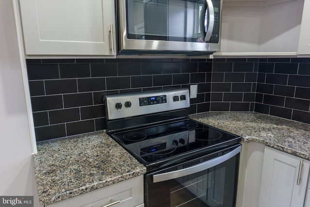 kitchen with stainless steel appliances, white cabinetry, and tasteful backsplash