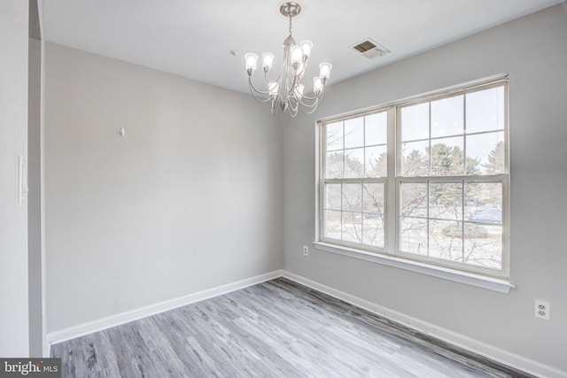 empty room featuring an inviting chandelier and light wood-type flooring