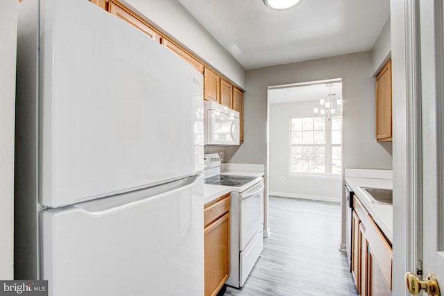 kitchen with sink, light wood-type flooring, a chandelier, and white appliances