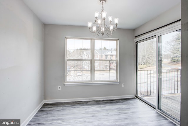 unfurnished dining area with wood-type flooring and a notable chandelier