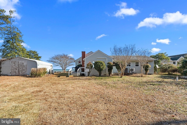 rear view of property featuring a yard and a storage unit