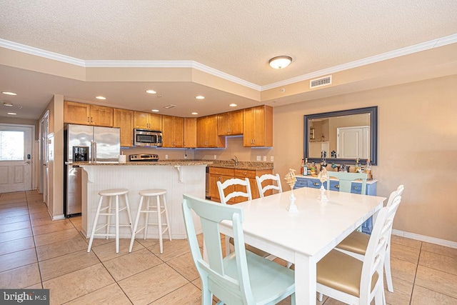 tiled dining area with sink, crown molding, and a textured ceiling