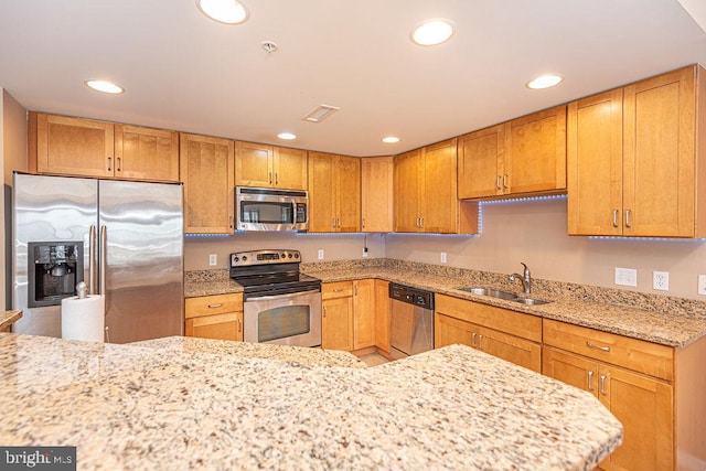 kitchen featuring stainless steel appliances, light stone countertops, and sink