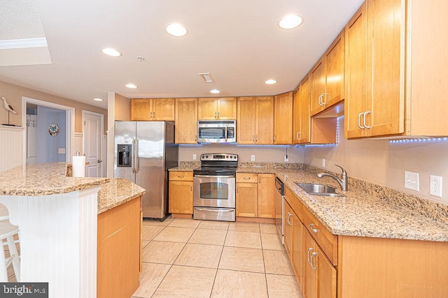 kitchen featuring sink, light tile patterned floors, a breakfast bar, stainless steel appliances, and light stone counters