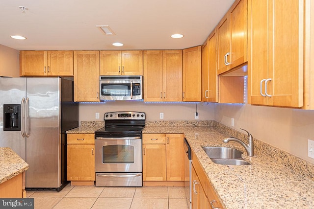 kitchen featuring light stone counters, sink, light tile patterned floors, and appliances with stainless steel finishes