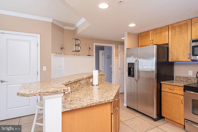 kitchen with stainless steel appliances, light stone countertops, a kitchen island, and a kitchen breakfast bar