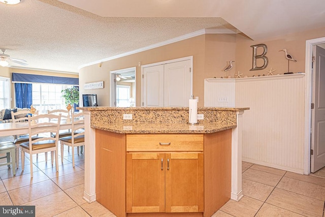 kitchen with light stone counters, ceiling fan, a textured ceiling, and light tile patterned floors