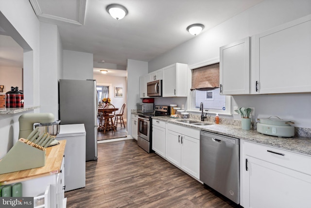 kitchen featuring sink, dark hardwood / wood-style floors, stainless steel appliances, light stone countertops, and white cabinets