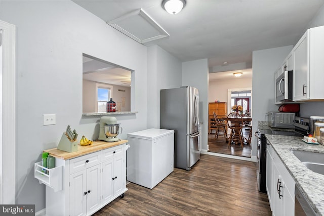 kitchen with dark wood-type flooring, a healthy amount of sunlight, appliances with stainless steel finishes, and white cabinets