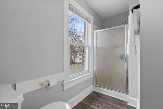 bathroom featuring hardwood / wood-style flooring, toilet, and a shower with shower door