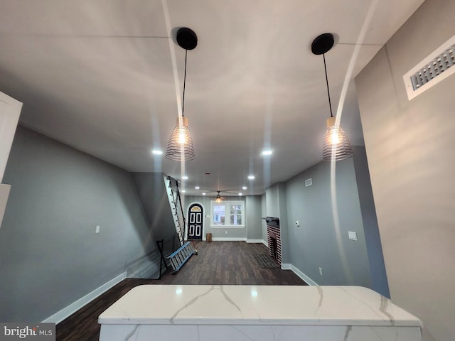 interior space featuring dark hardwood / wood-style flooring, hanging light fixtures, light stone countertops, and ceiling fan