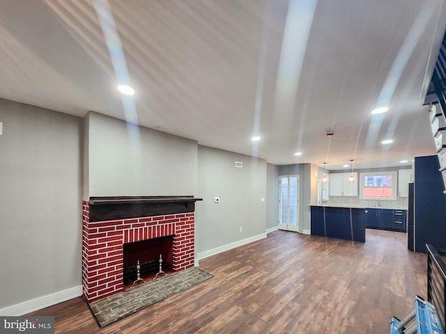 unfurnished living room with a brick fireplace and dark hardwood / wood-style flooring