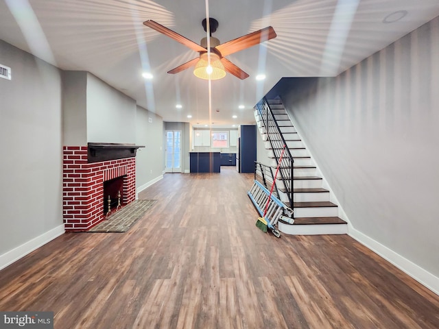 unfurnished living room featuring hardwood / wood-style flooring, ceiling fan, and a fireplace