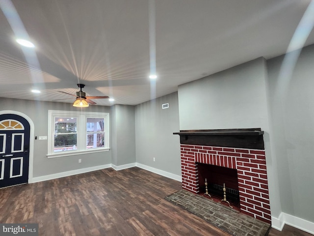 unfurnished living room featuring ceiling fan, dark hardwood / wood-style floors, and a brick fireplace