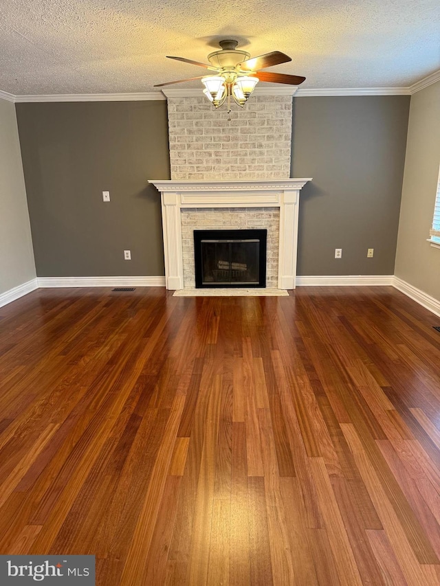 unfurnished living room featuring ornamental molding, visible vents, wood finished floors, and a brick fireplace