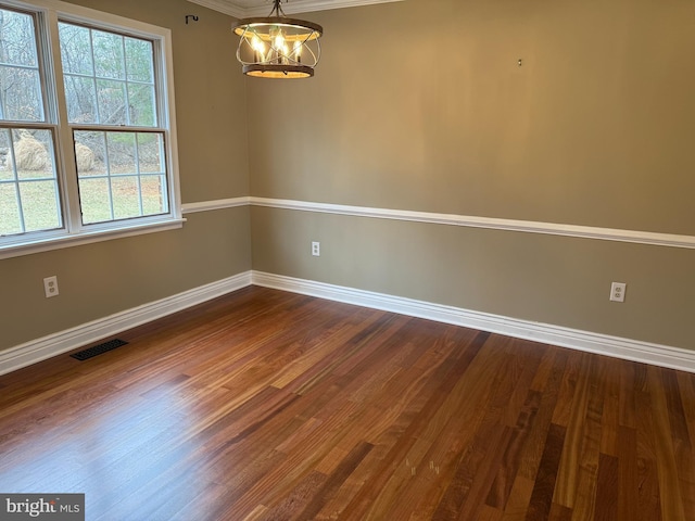 spare room featuring baseboards, visible vents, and wood finished floors