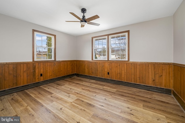 empty room featuring hardwood / wood-style flooring, ceiling fan, and wood walls