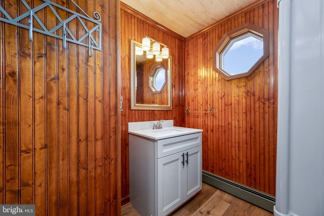 bathroom with hardwood / wood-style flooring, a baseboard radiator, vanity, and wooden walls