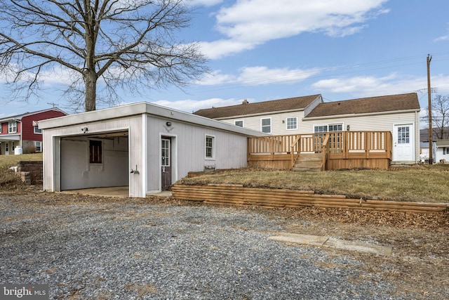 rear view of property with a wooden deck and a garage