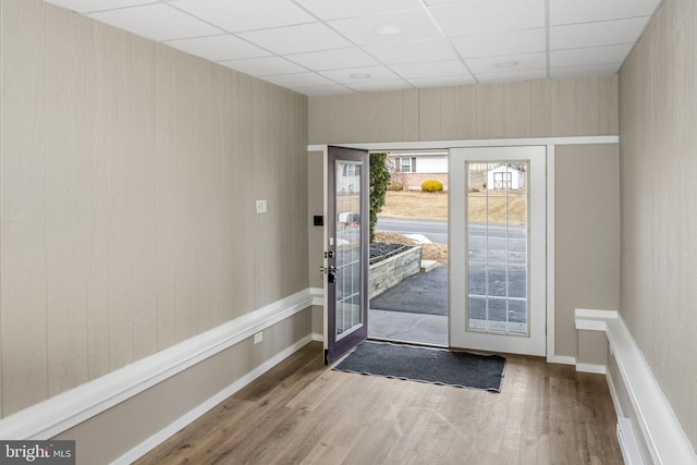 doorway to outside with hardwood / wood-style floors and a drop ceiling