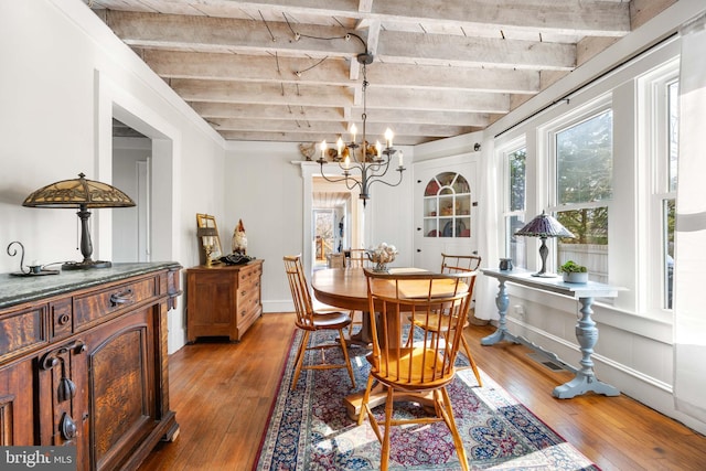 dining space featuring a notable chandelier, beam ceiling, and light hardwood / wood-style flooring