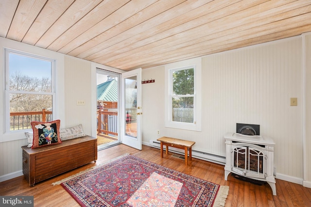 living area featuring hardwood / wood-style floors, a baseboard radiator, wooden ceiling, and a wood stove