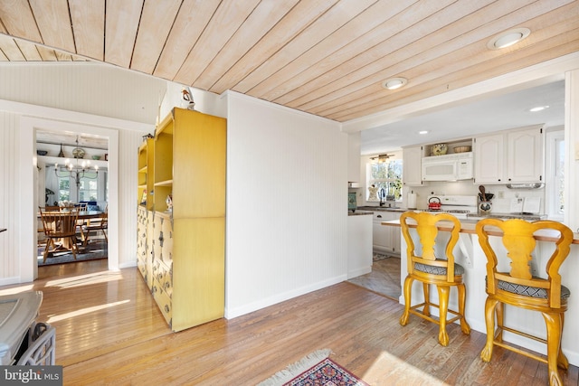 dining room featuring wood ceiling, sink, an inviting chandelier, and light wood-type flooring