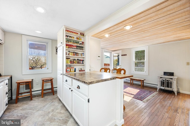 kitchen with light hardwood / wood-style flooring, a baseboard radiator, dark stone countertops, and white cabinets