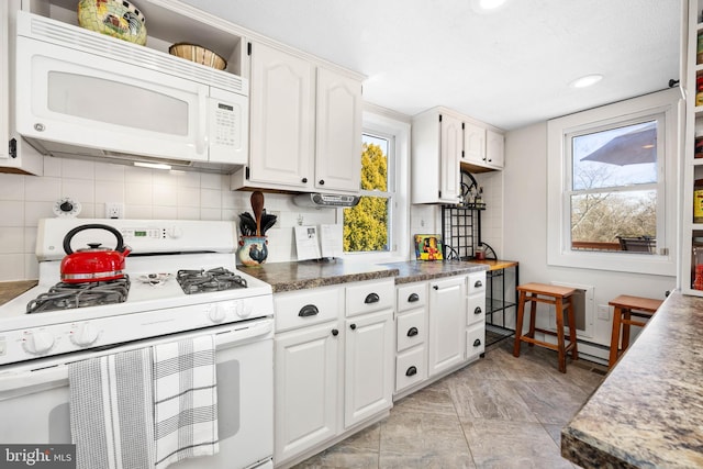 kitchen featuring tasteful backsplash, white appliances, and white cabinets