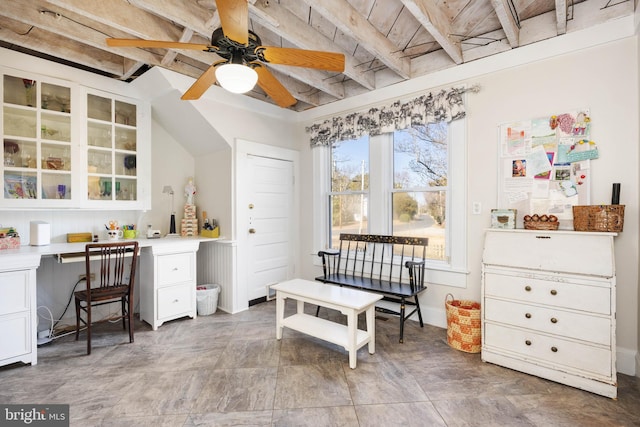 interior space with beam ceiling, built in desk, and ceiling fan