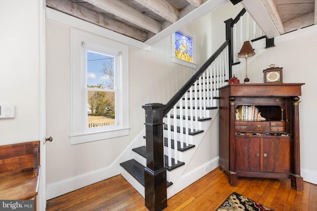 staircase featuring beamed ceiling and hardwood / wood-style floors