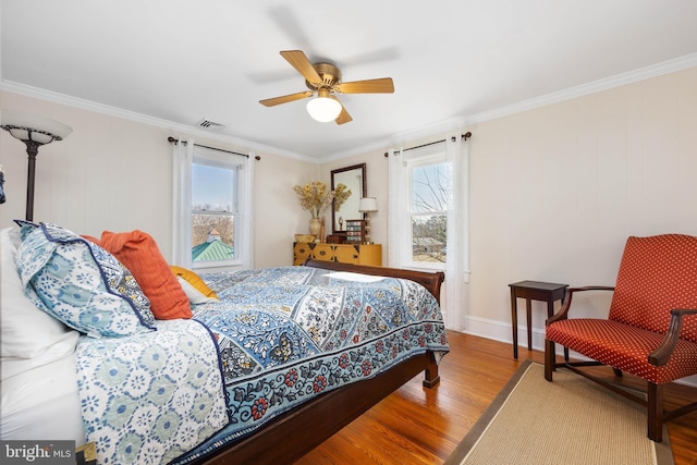 bedroom featuring multiple windows, wood-type flooring, ornamental molding, and ceiling fan