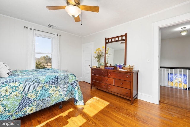 bedroom with ornamental molding, hardwood / wood-style floors, and ceiling fan