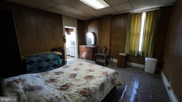 bedroom with a drop ceiling and wood walls