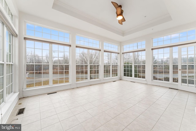 unfurnished sunroom with a wealth of natural light, a raised ceiling, and ceiling fan