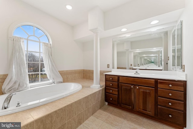 bathroom with vanity, tile patterned flooring, a relaxing tiled tub, and decorative columns