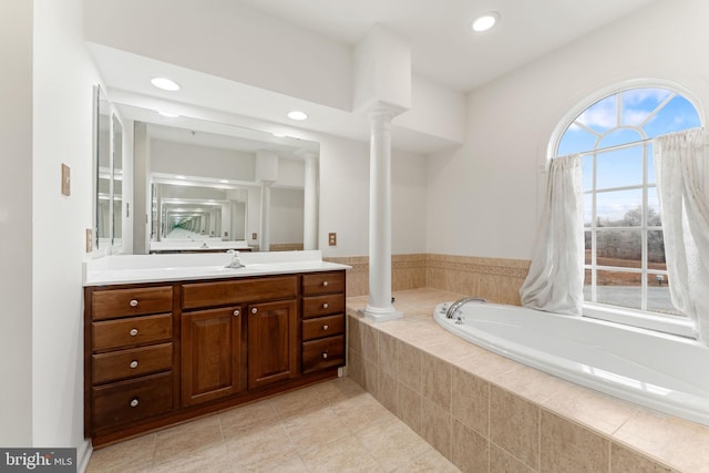 bathroom featuring decorative columns, vanity, tile patterned flooring, and a relaxing tiled tub