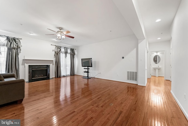 unfurnished living room featuring ceiling fan, sink, hardwood / wood-style floors, and a fireplace