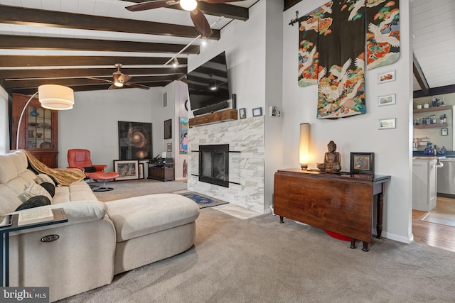 living room featuring beamed ceiling, light colored carpet, and ceiling fan