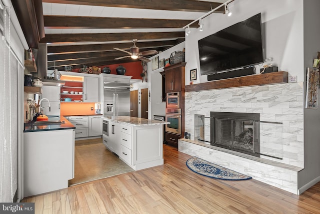 kitchen with sink, a center island, lofted ceiling with beams, light hardwood / wood-style floors, and white cabinets