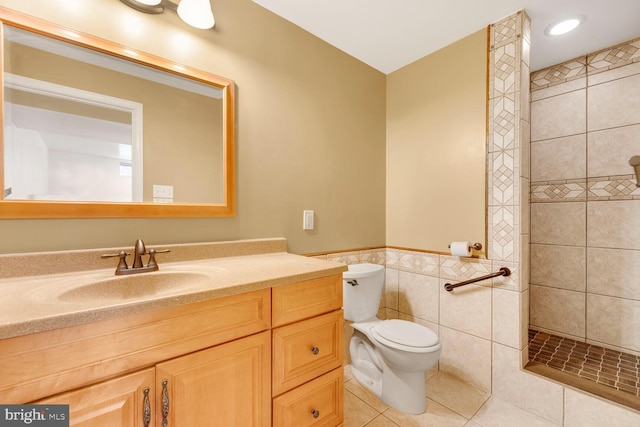 bathroom featuring a tile shower, tile walls, tile patterned flooring, vanity, and toilet