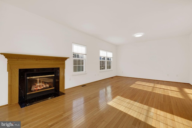 unfurnished living room featuring a premium fireplace and wood-type flooring