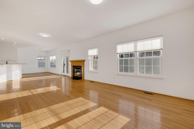 unfurnished living room with light hardwood / wood-style flooring and a notable chandelier