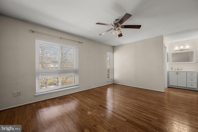 unfurnished bedroom with ceiling fan, connected bathroom, sink, and hardwood / wood-style floors