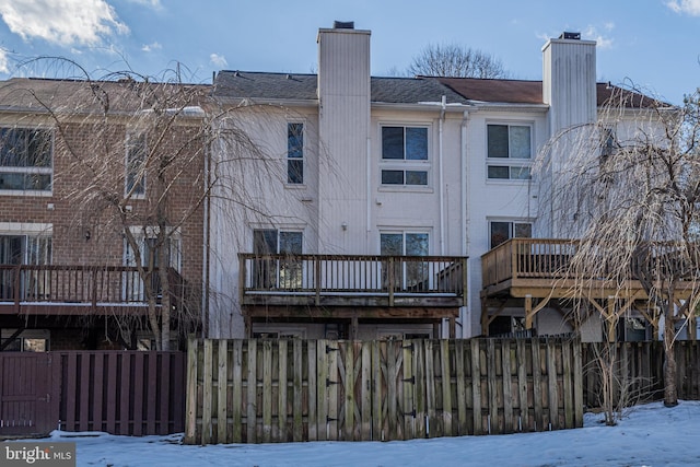 snow covered back of property with a balcony