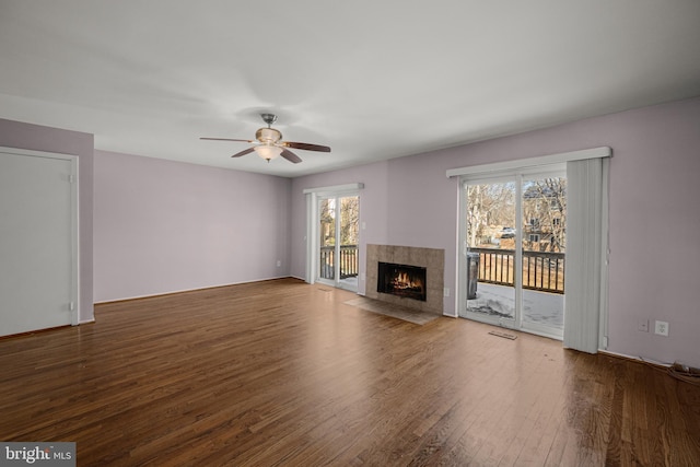 unfurnished living room with wood-type flooring, a tile fireplace, and ceiling fan