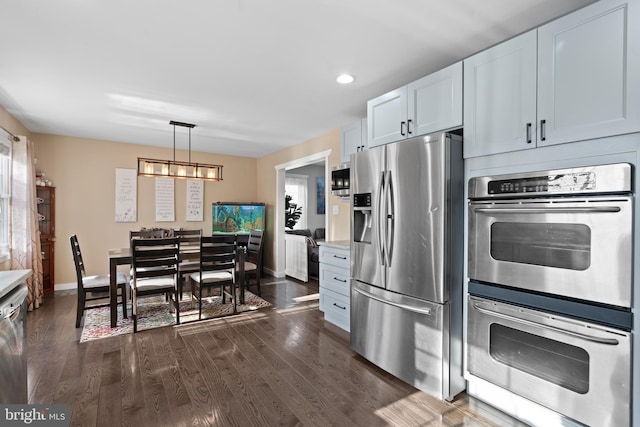 kitchen featuring dark wood-type flooring, an inviting chandelier, hanging light fixtures, stainless steel appliances, and white cabinets