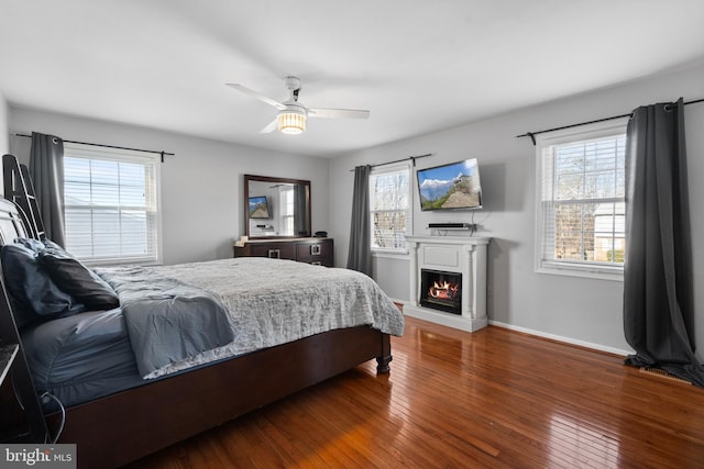 bedroom featuring ceiling fan, dark hardwood / wood-style floors, and multiple windows